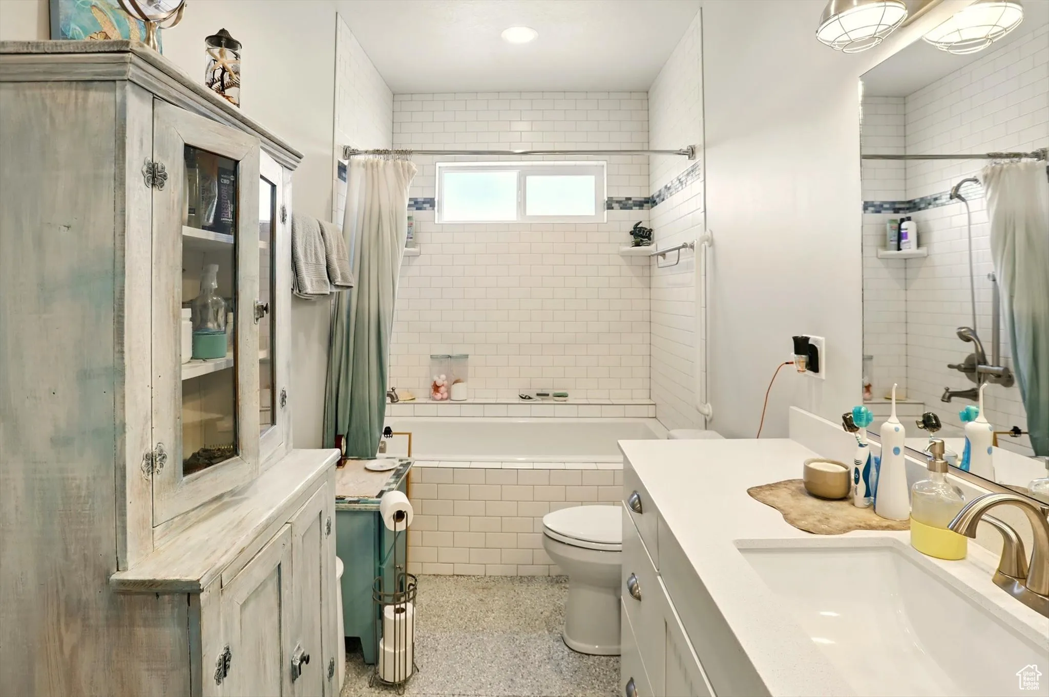 Full bathroom featuring tiled shower / bath, vanity, toilet, and speckle patterned floor