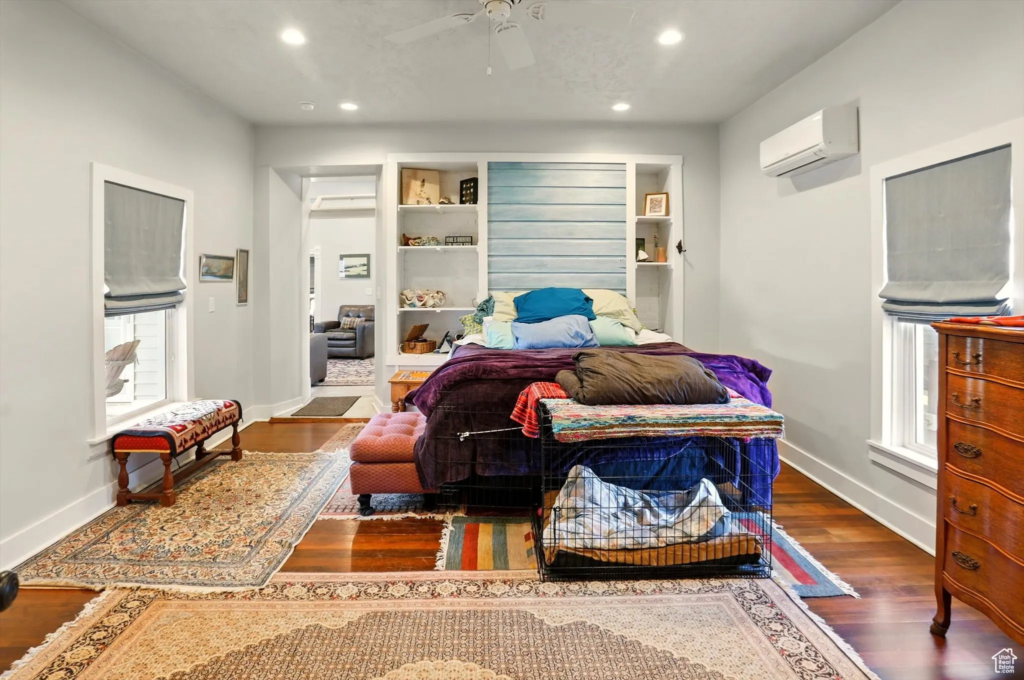 Bedroom with recessed lighting, wood finished floors, a wall unit AC, baseboards, and multiple windows