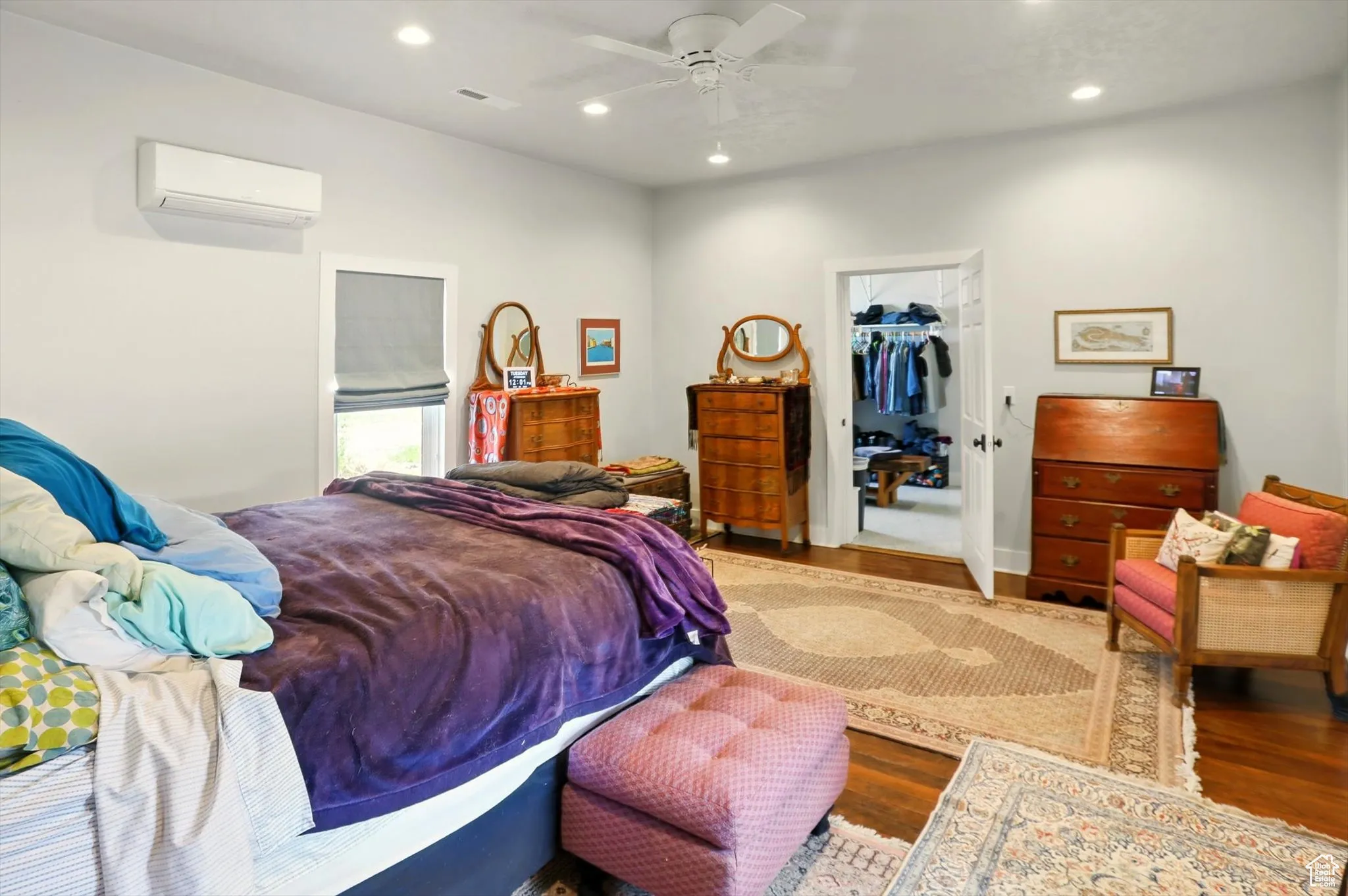 Bedroom featuring a wall mounted air conditioner, wood finished floors, recessed lighting, a walk in closet, and a closet