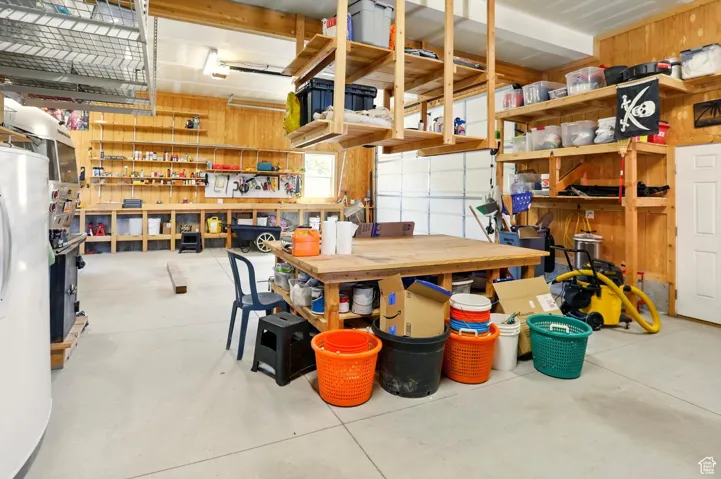 Garage featuring a workshop area, fridge, and wood walls