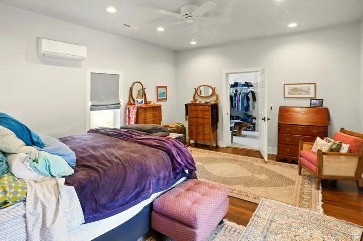 Bedroom featuring a wall mounted air conditioner, wood finished floors, recessed lighting, a walk in closet, and a closet