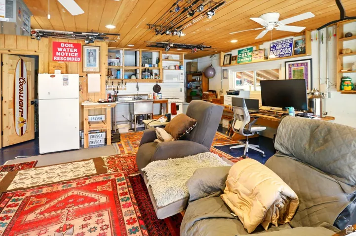 Living room with a ceiling fan, wooden ceiling, a garage, an office area, and recessed lighting