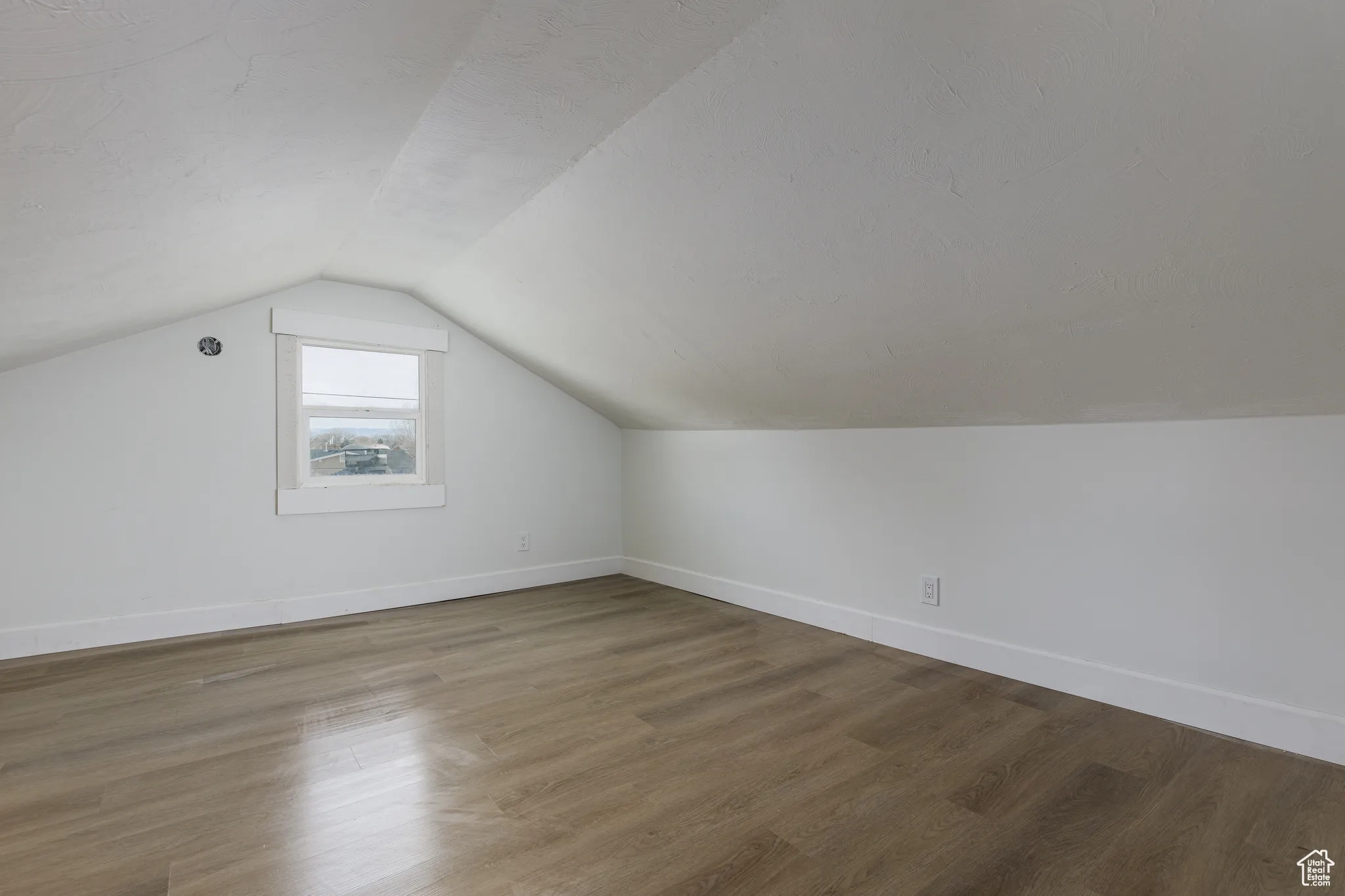 Bonus room with vaulted ceiling, baseboards, and wood finished floors