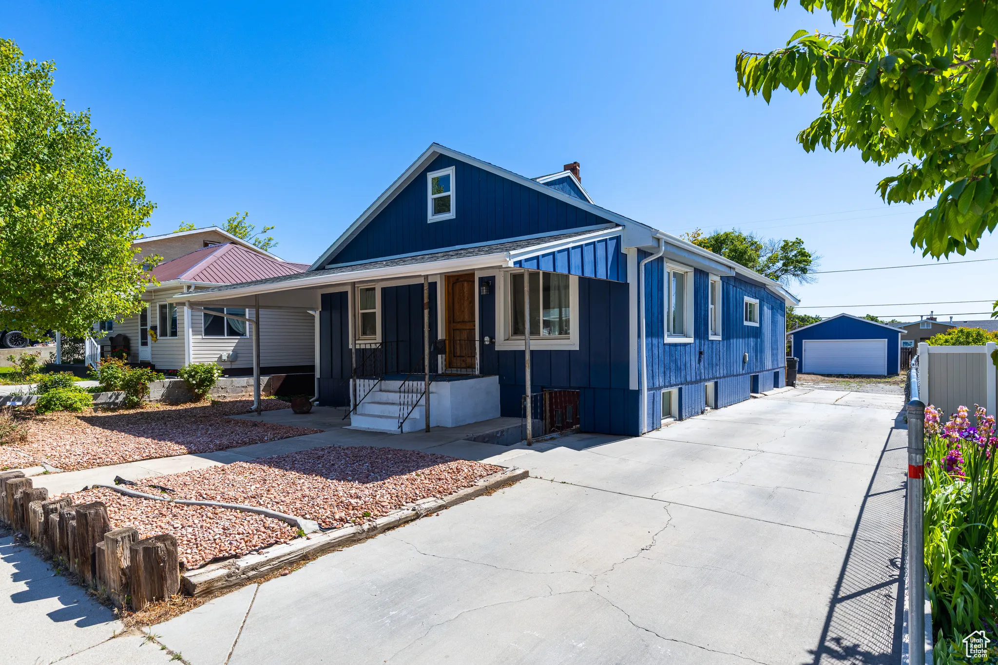 View of front facade with covered porch, board and batten siding, an outbuilding, driveway, and a garage