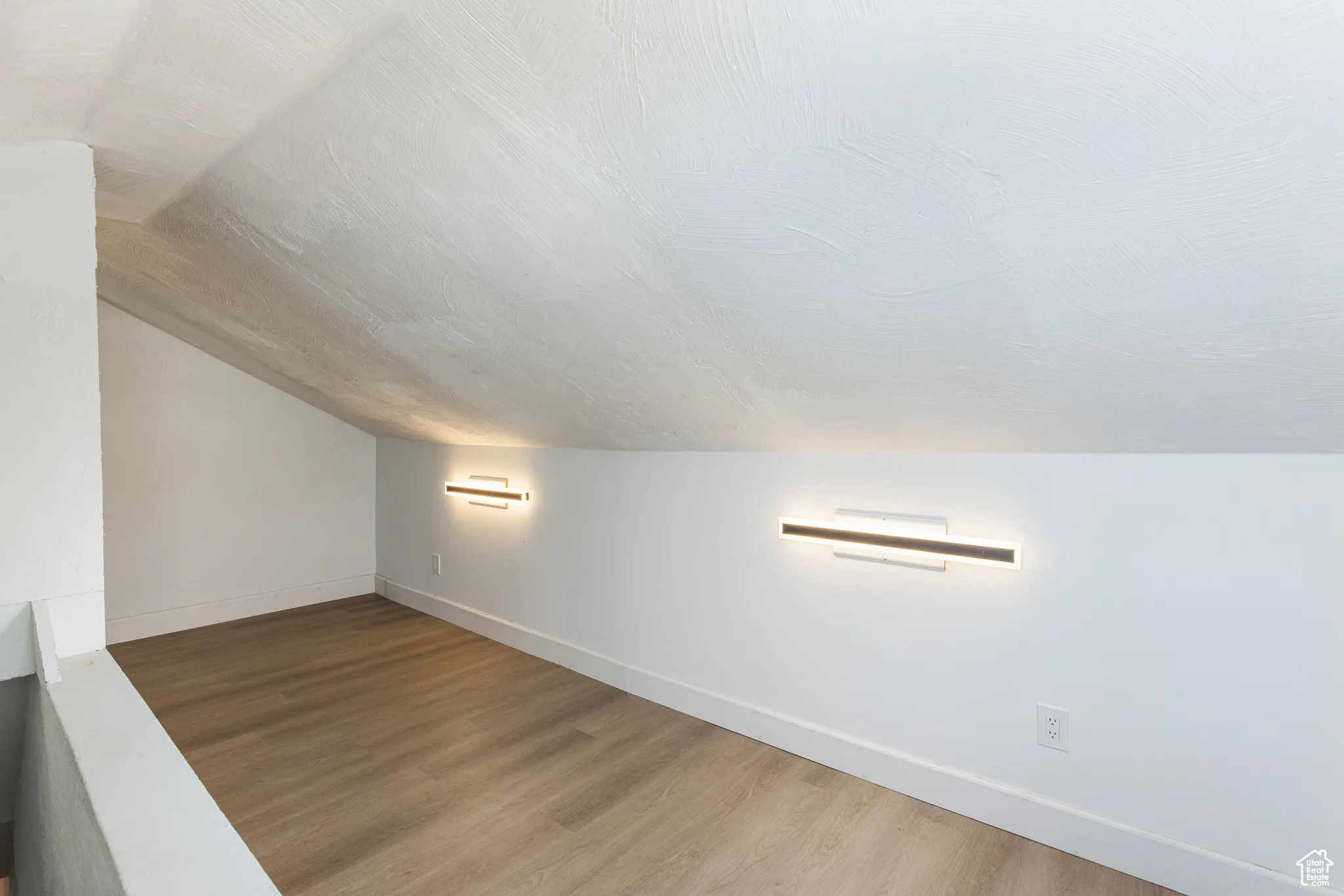 Additional living space featuring lofted ceiling, light wood-type flooring, and baseboards