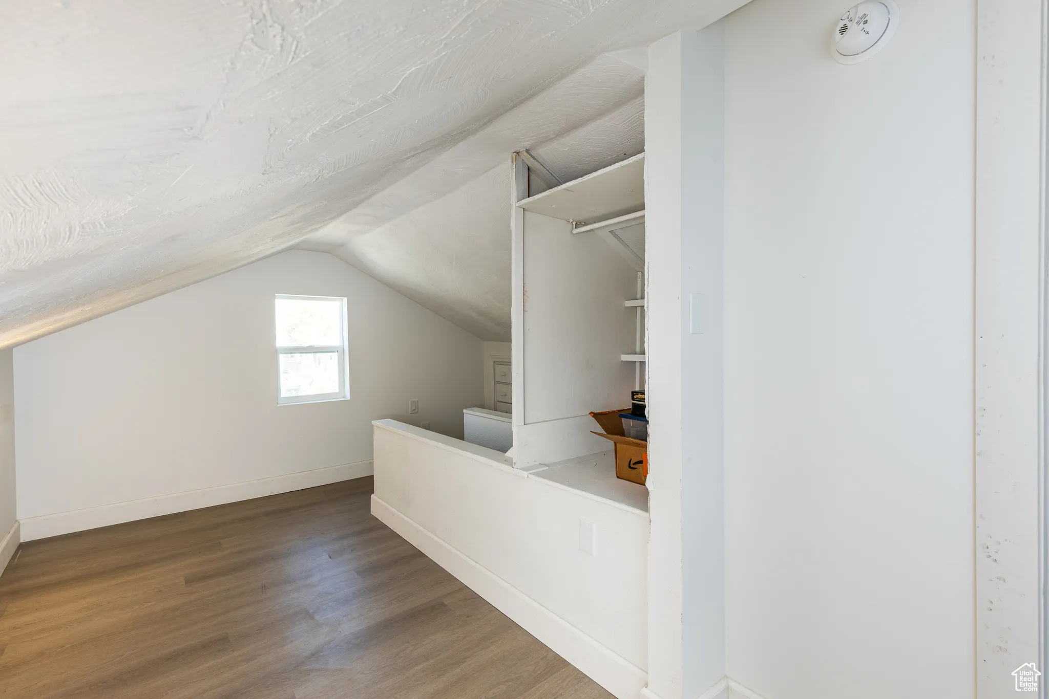 Additional living space with wood finished floors, lofted ceiling, and baseboards