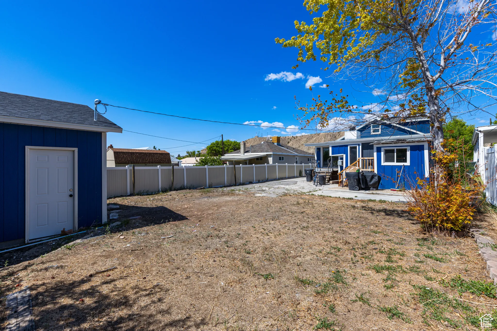 Fenced backyard with a patio area, an outbuilding, and entry steps