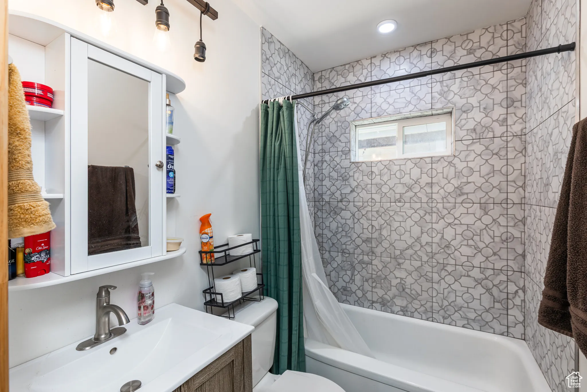 Bathroom with toilet, shower / bath combo with shower curtain, and vanity