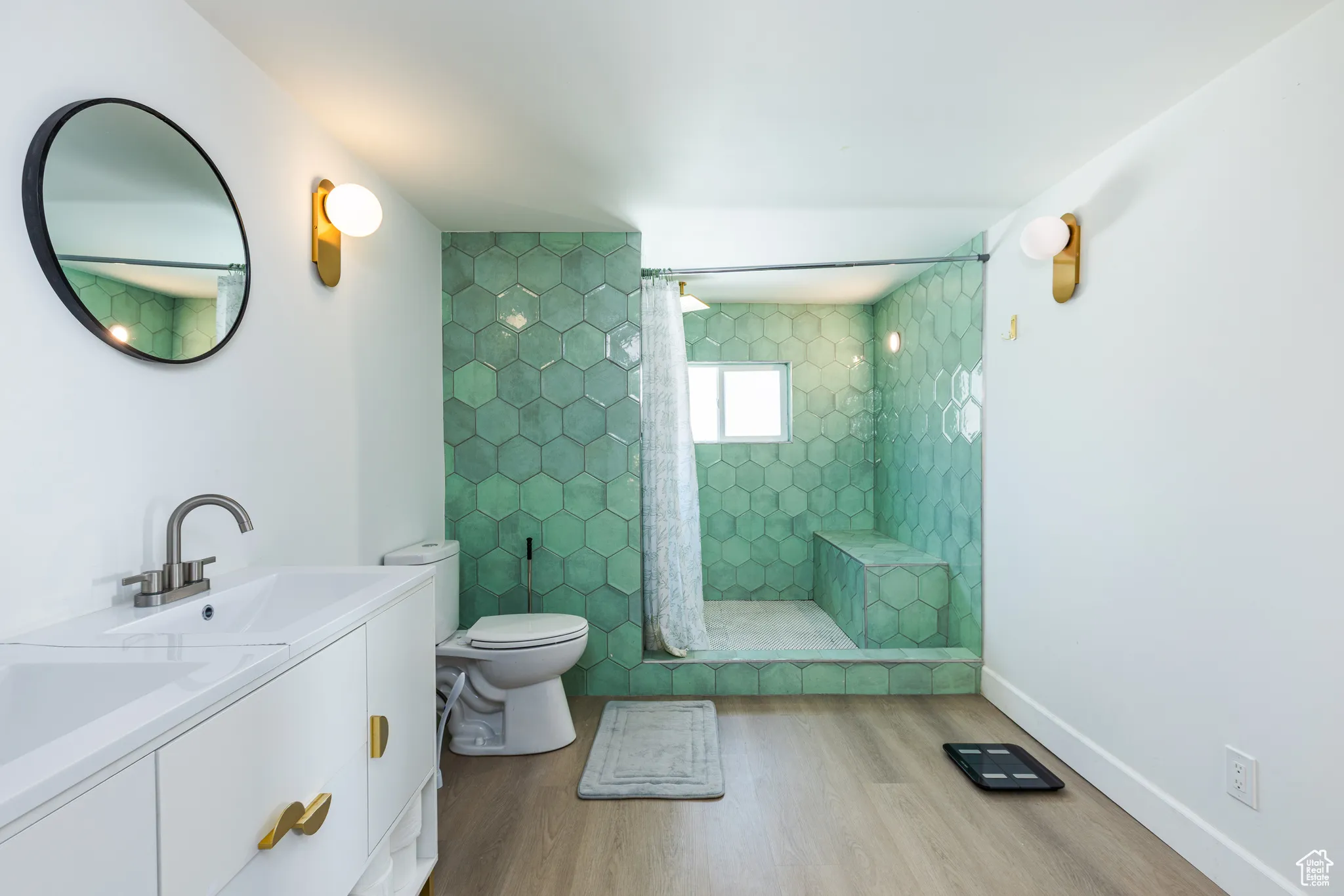 Full bathroom featuring wood finished floors, toilet, tiled shower, and vanity