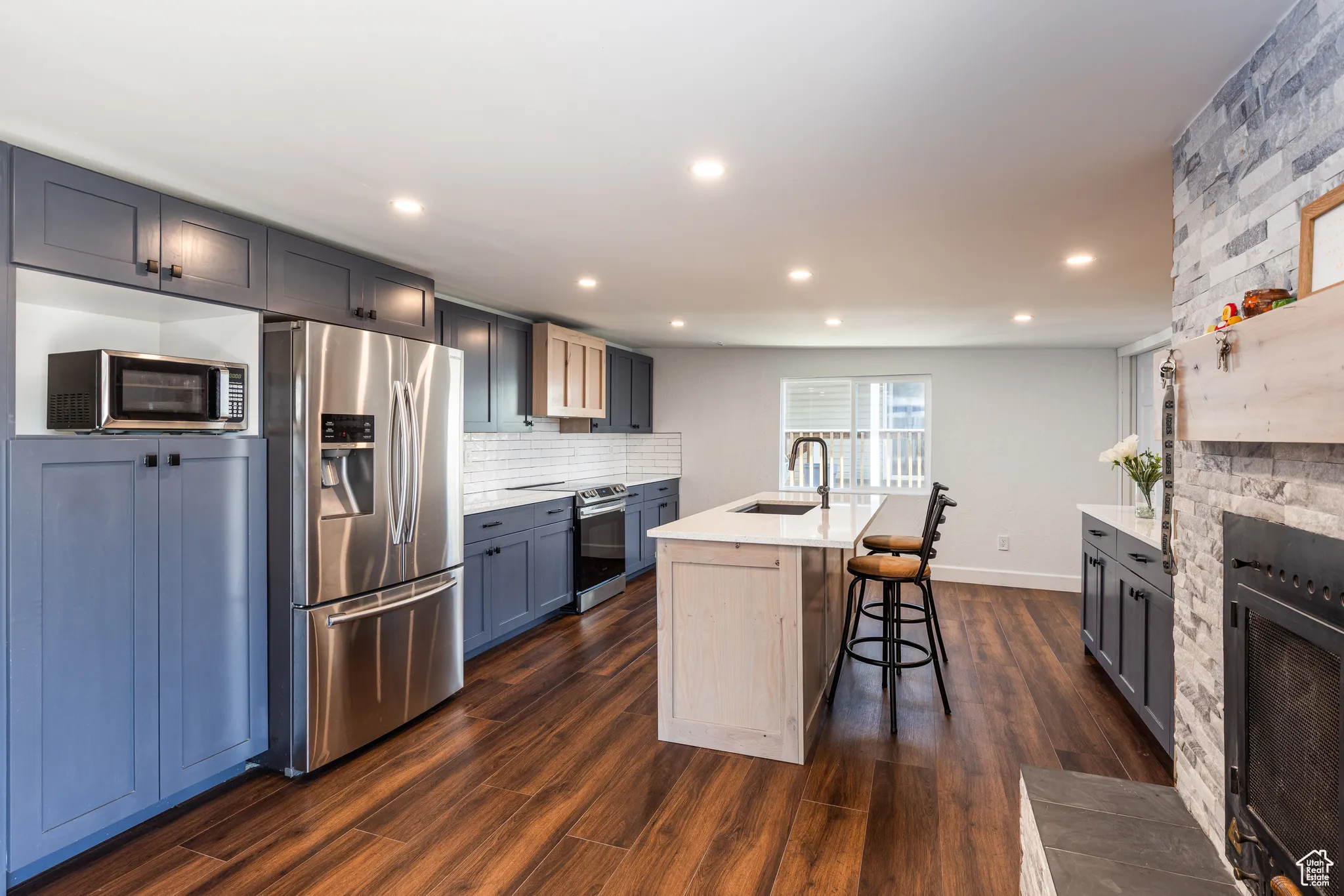 Kitchen featuring appliances with stainless steel finishes, a sink, light countertops, decorative backsplash, and a breakfast bar area