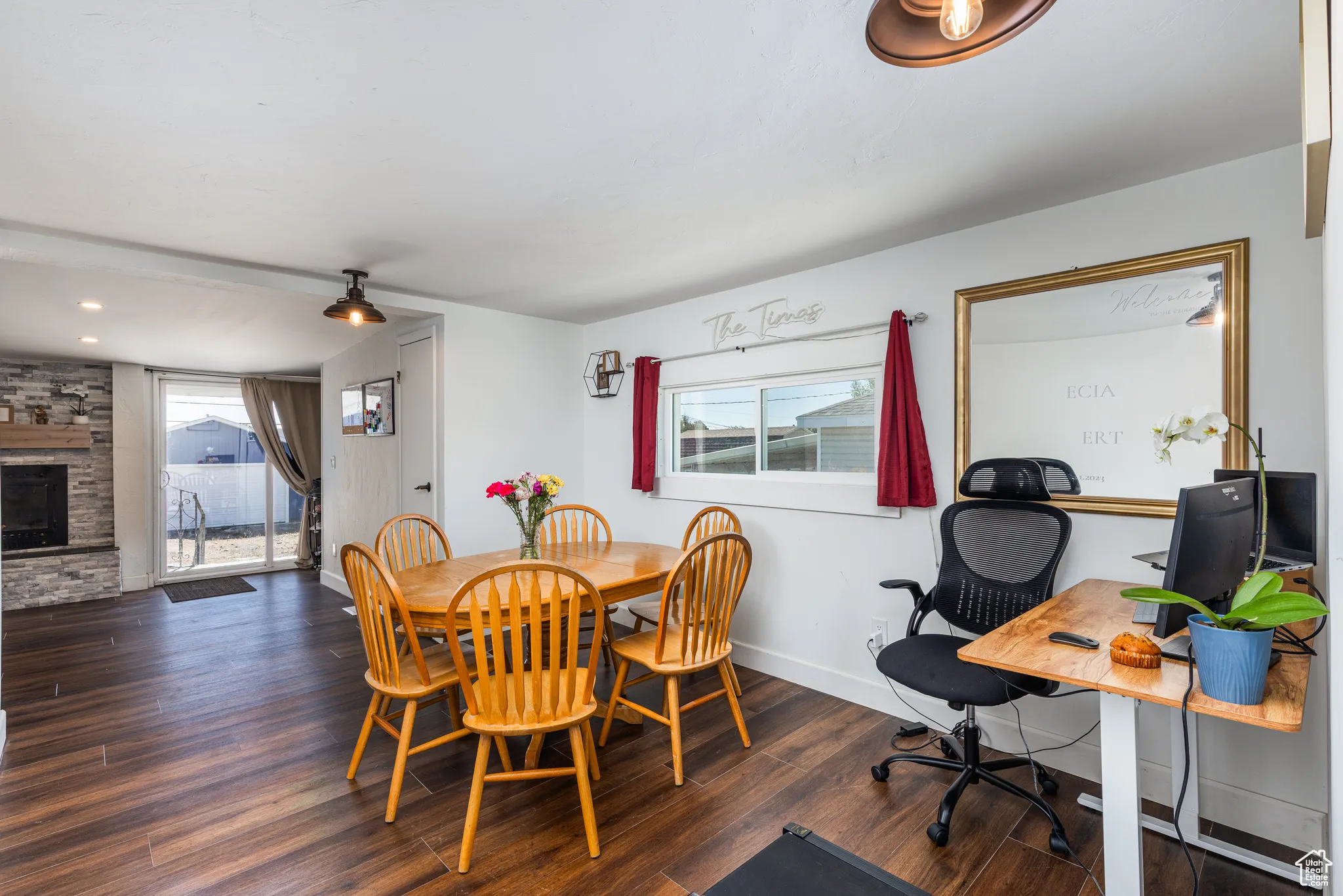 Dining area featuring wood finished floors, baseboards, an office area, and a stone fireplace