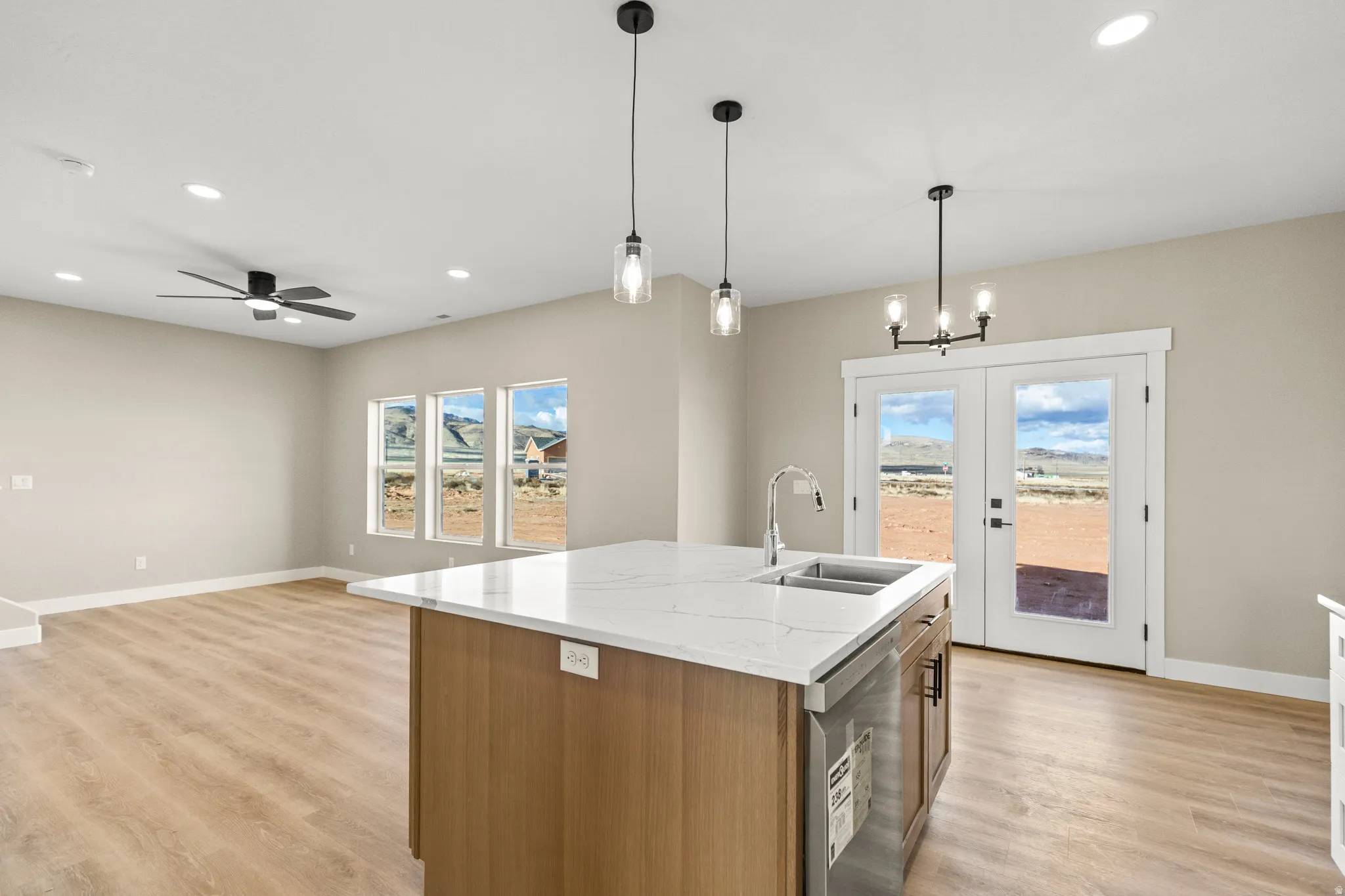 Kitchen featuring brown cabinetry, recessed lighting, pendant lighting, french doors, and light wood-style floors