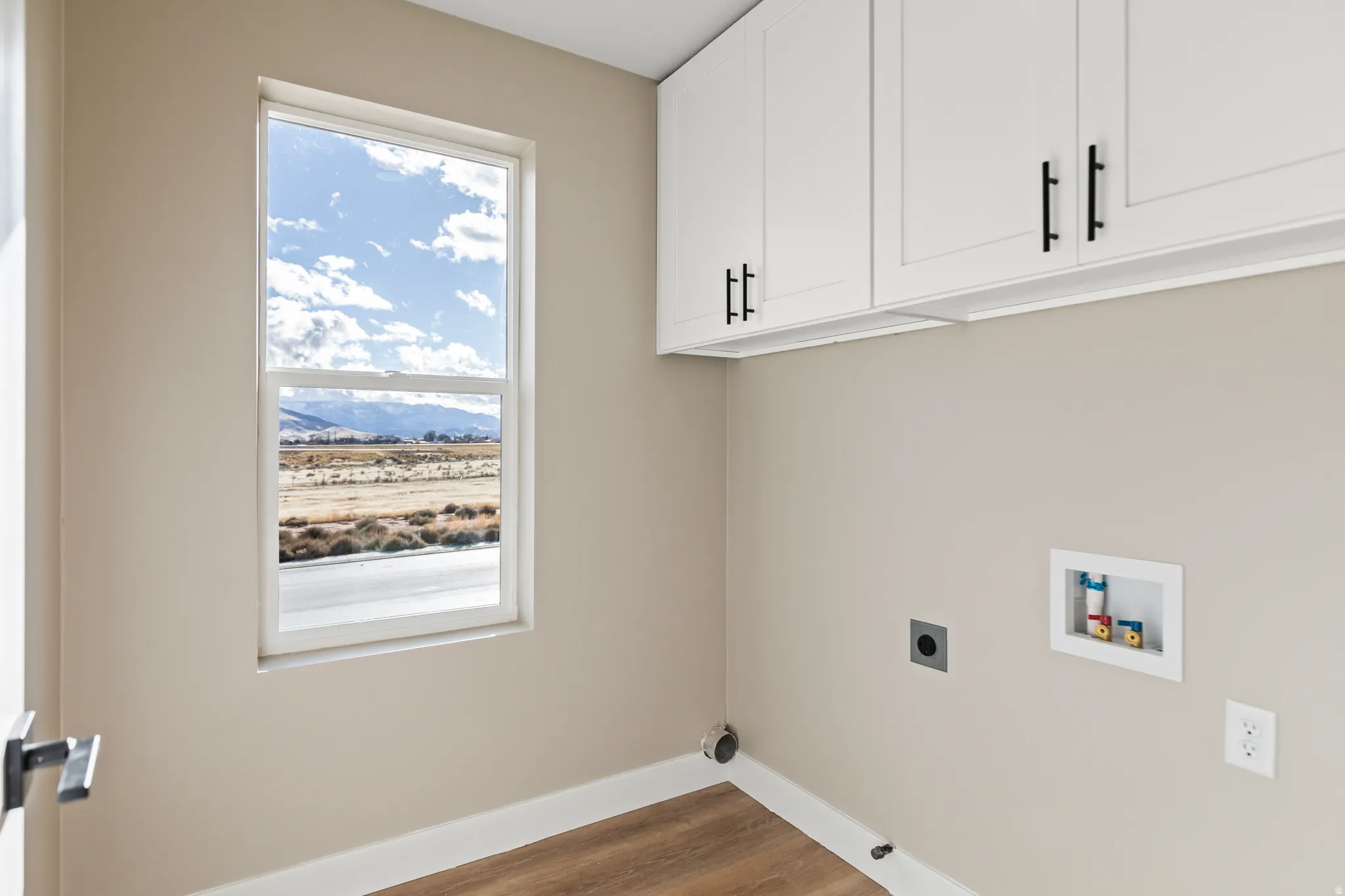 Laundry room featuring dark wood finished floors, electric dryer hookup, hookup for a washing machine, and cabinet space