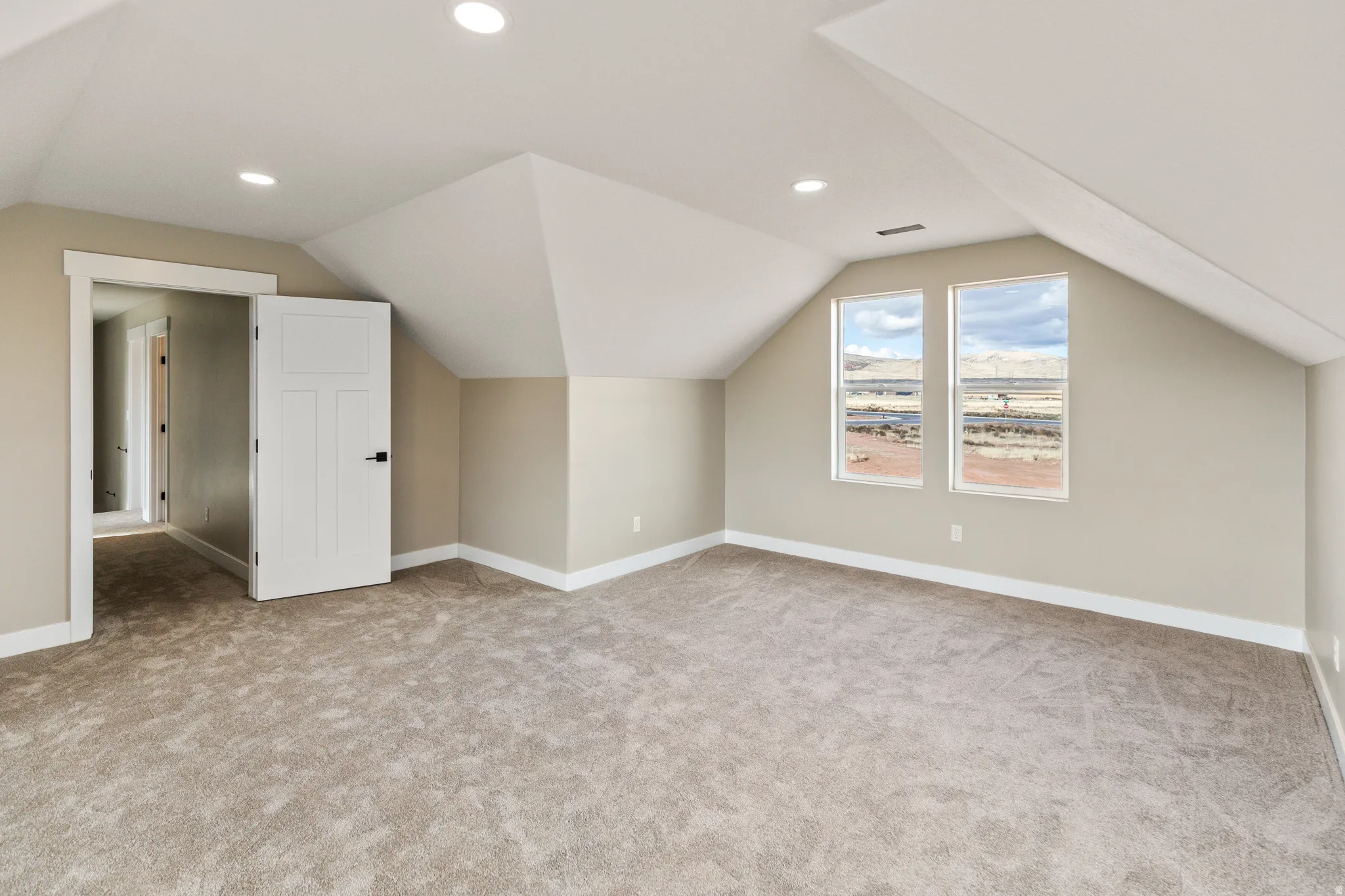 Bonus room with lofted ceiling, light carpet, and recessed lighting