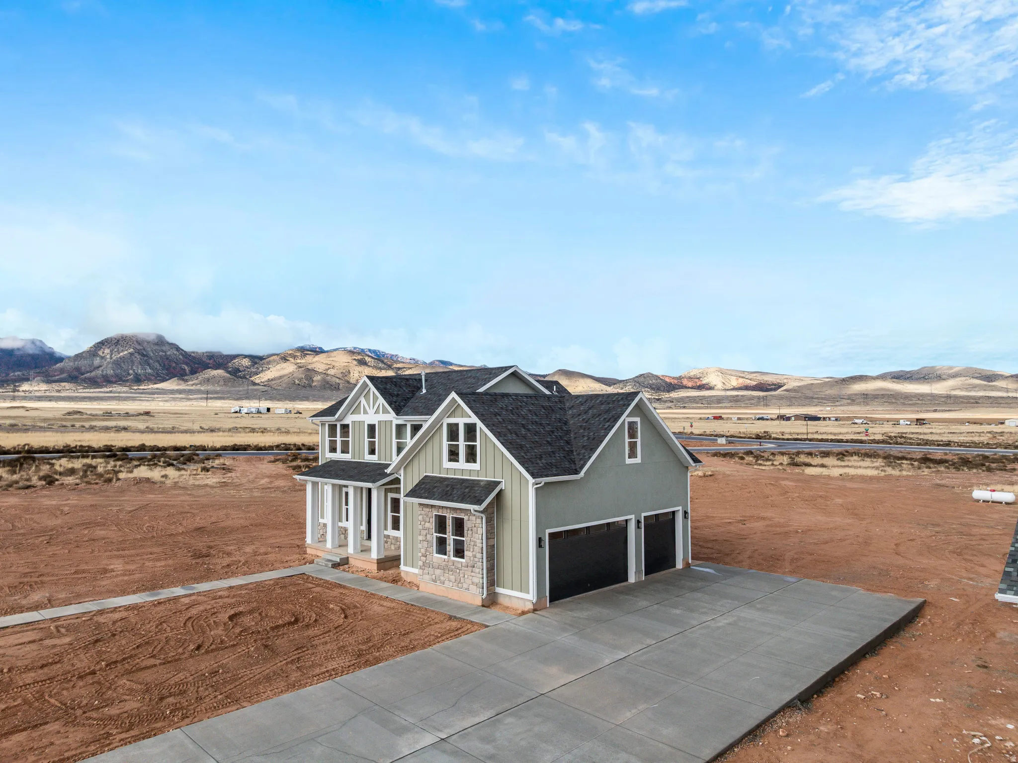 View of front facade featuring board and batten siding, a mountain view, stone siding, a garage, and driveway
