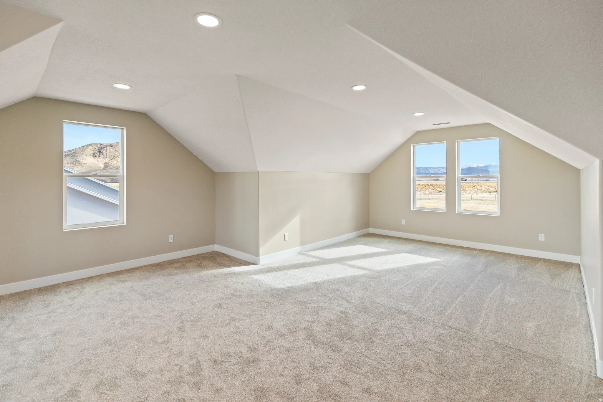 Bonus room featuring lofted ceiling, healthy amount of natural light, light colored carpet, and recessed lighting