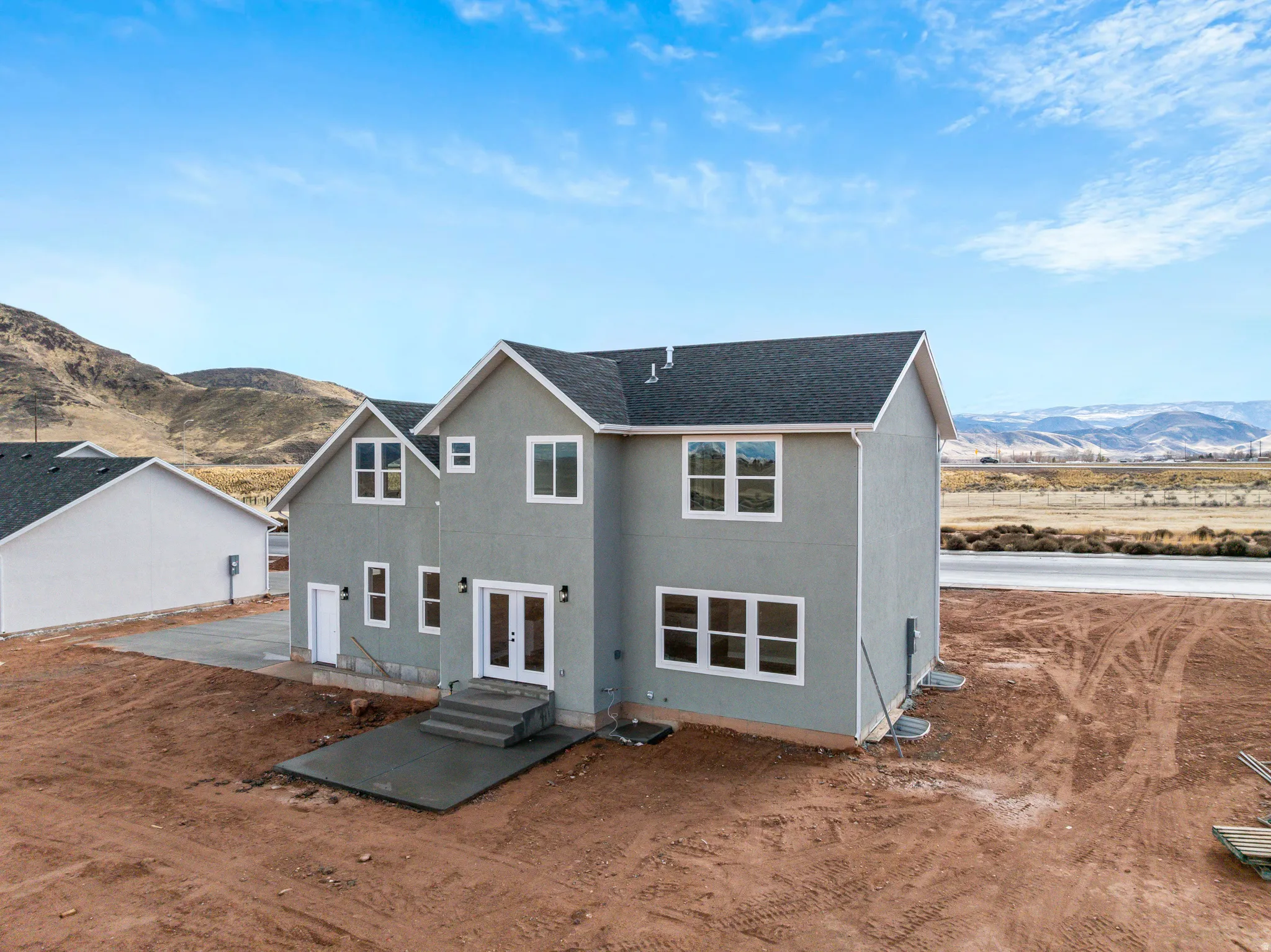 Rear view of house featuring a mountain view, roof with shingles, stucco siding, and french doors