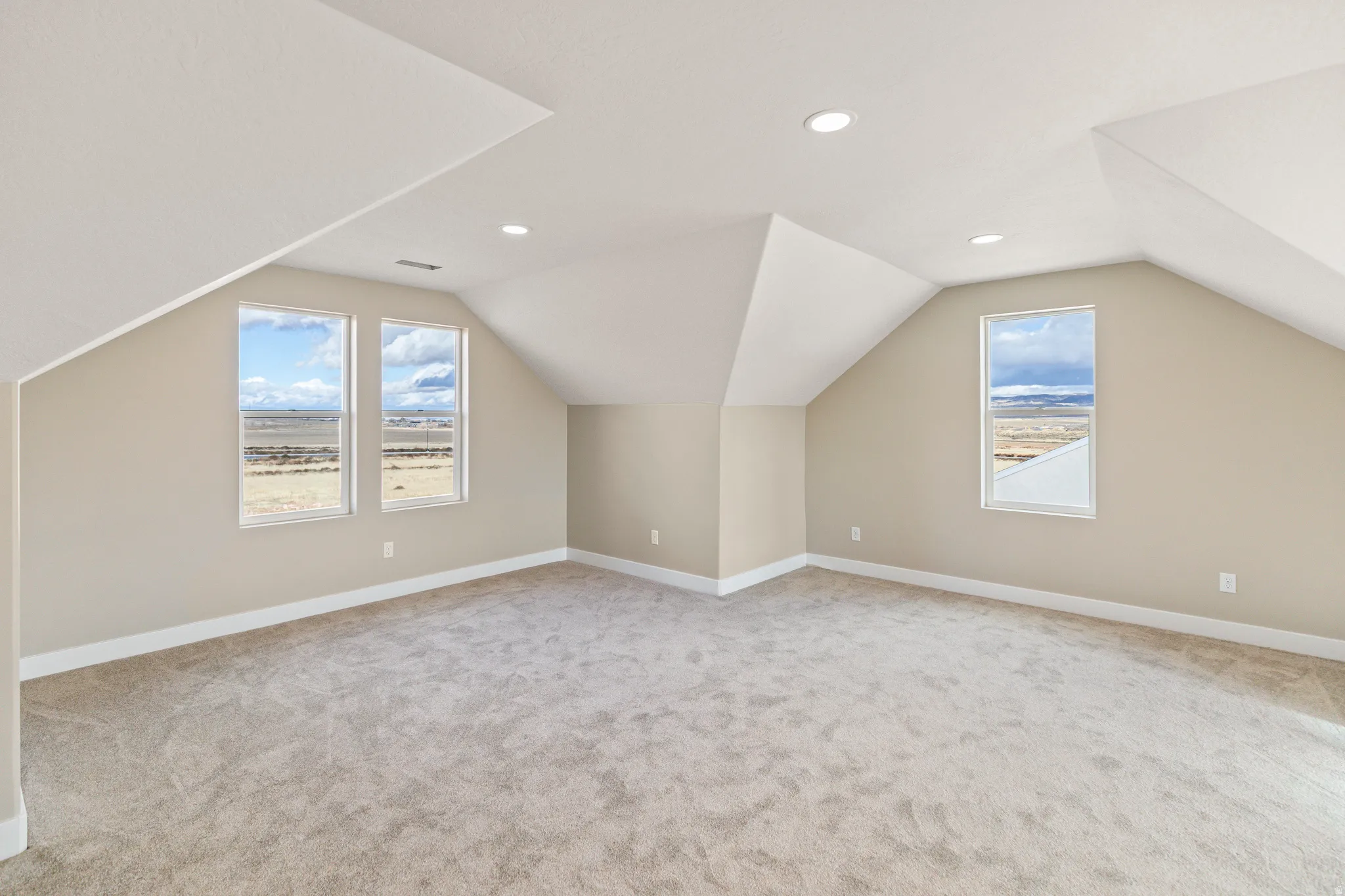 Additional living space with lofted ceiling, plenty of natural light, light carpet, and recessed lighting