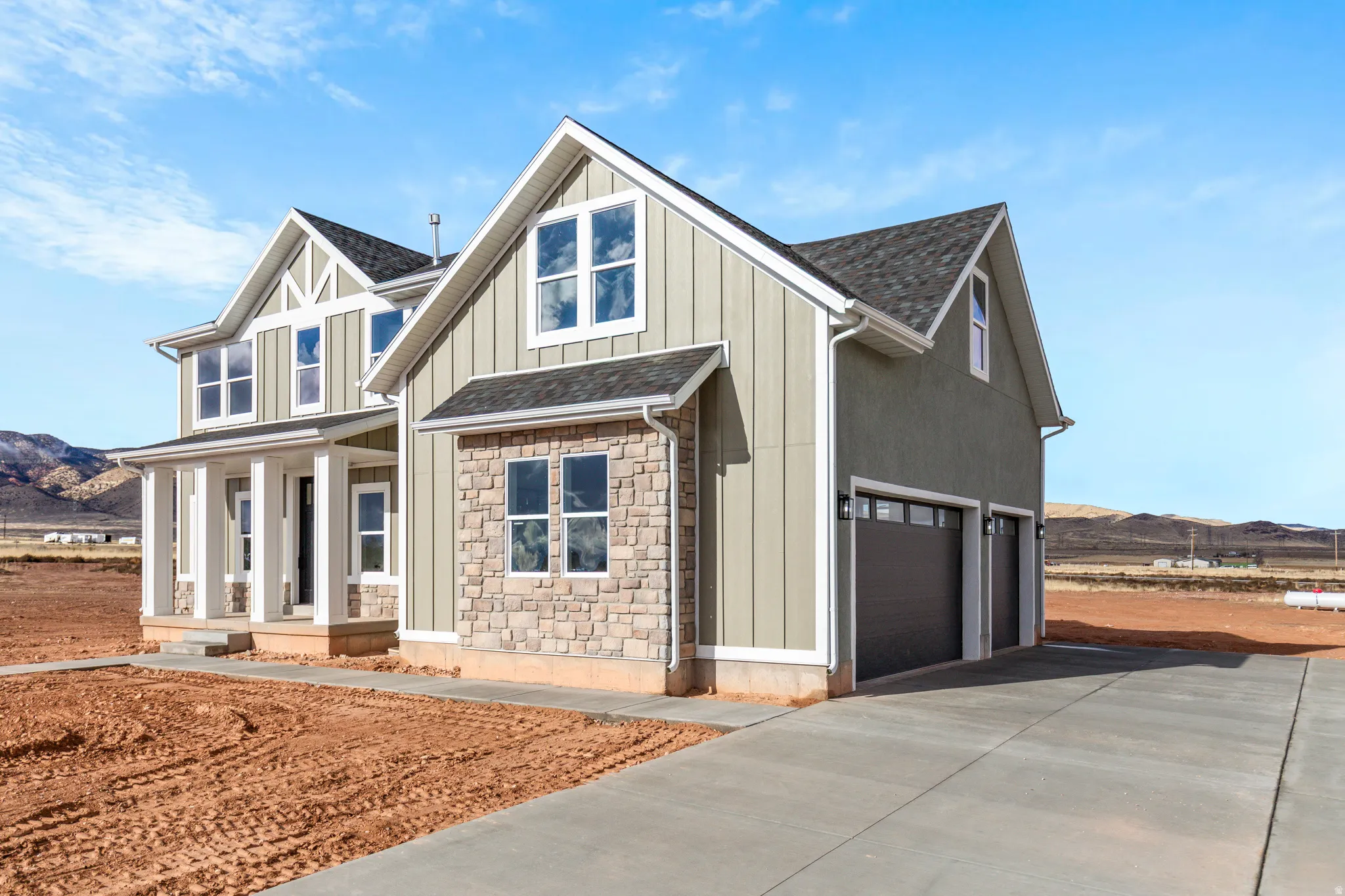 View of front of house featuring a mountain view, a porch, concrete driveway, and board and batten siding
