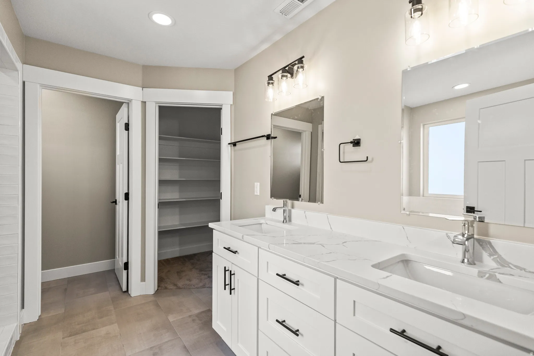Full bath with double vanity, recessed lighting, and a spacious closet