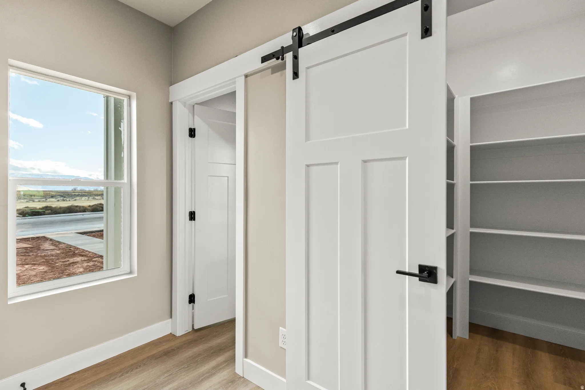 Hallway with light wood-style flooring and a barn door