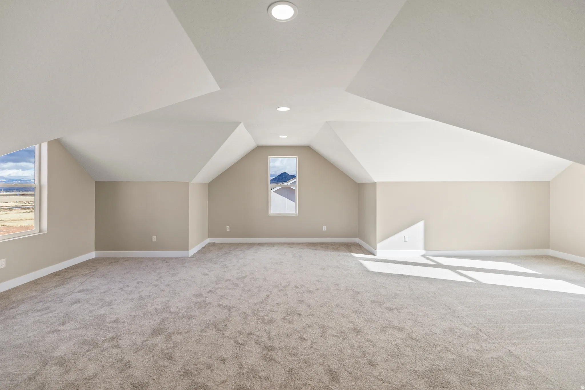 Bonus room with lofted ceiling, light colored carpet, and recessed lighting