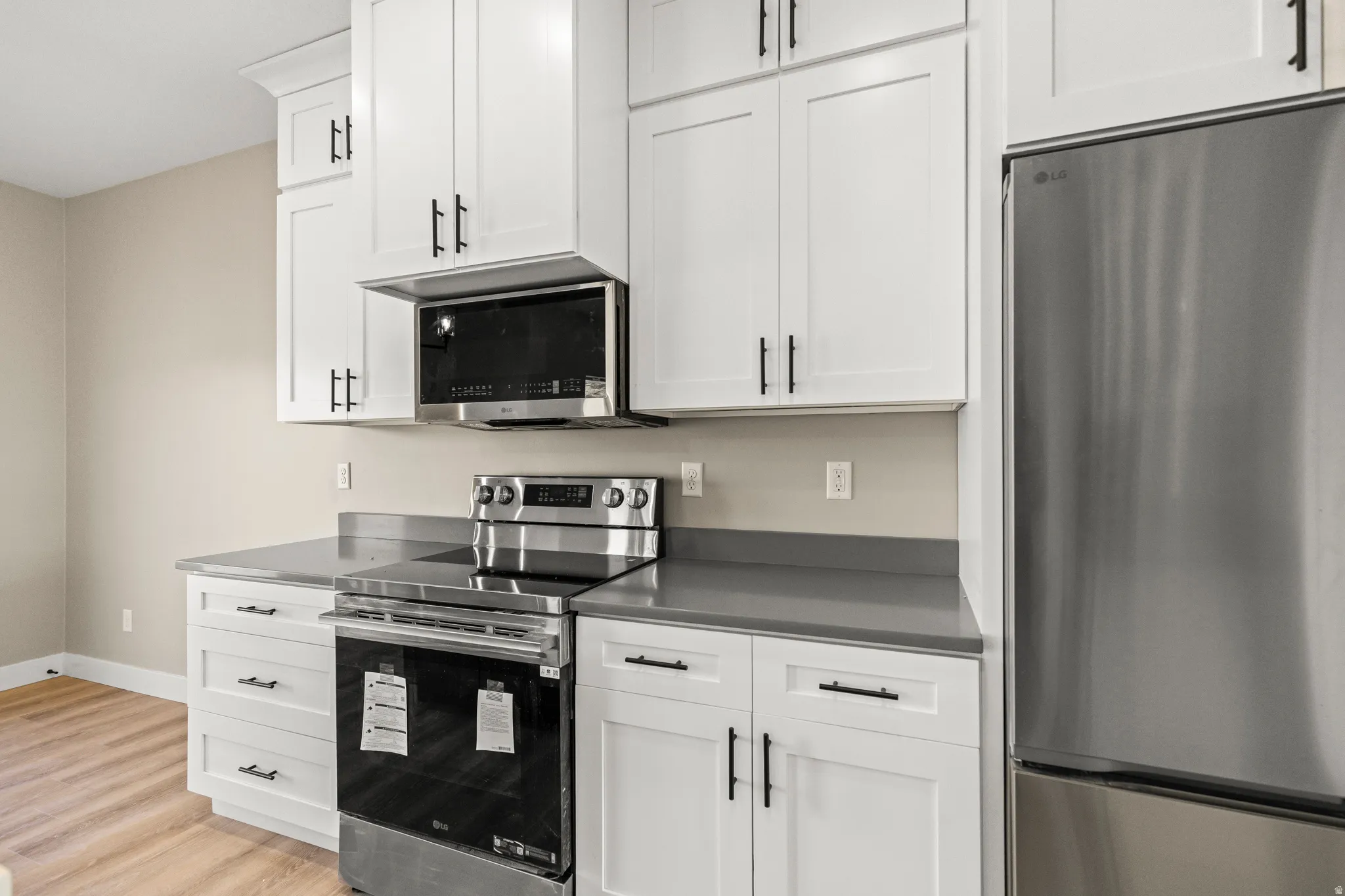 Kitchen with stainless steel appliances, white cabinetry, and light wood-type flooring
