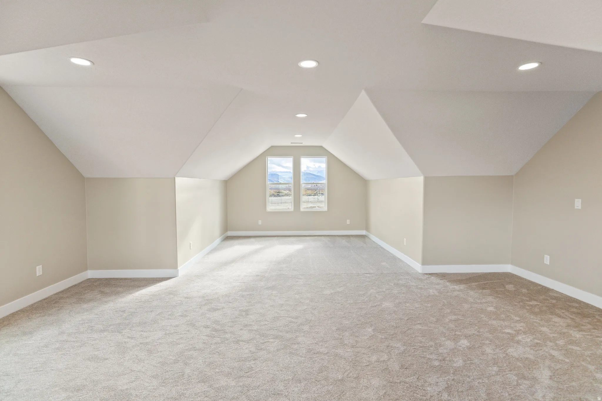 Additional living space with lofted ceiling, recessed lighting, and light colored carpet