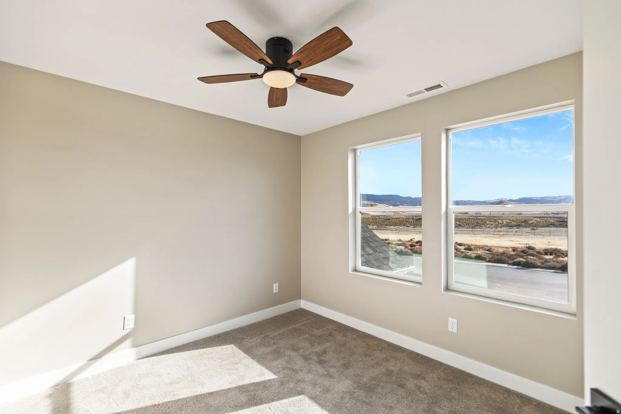 Empty room with carpet floors and ceiling fan