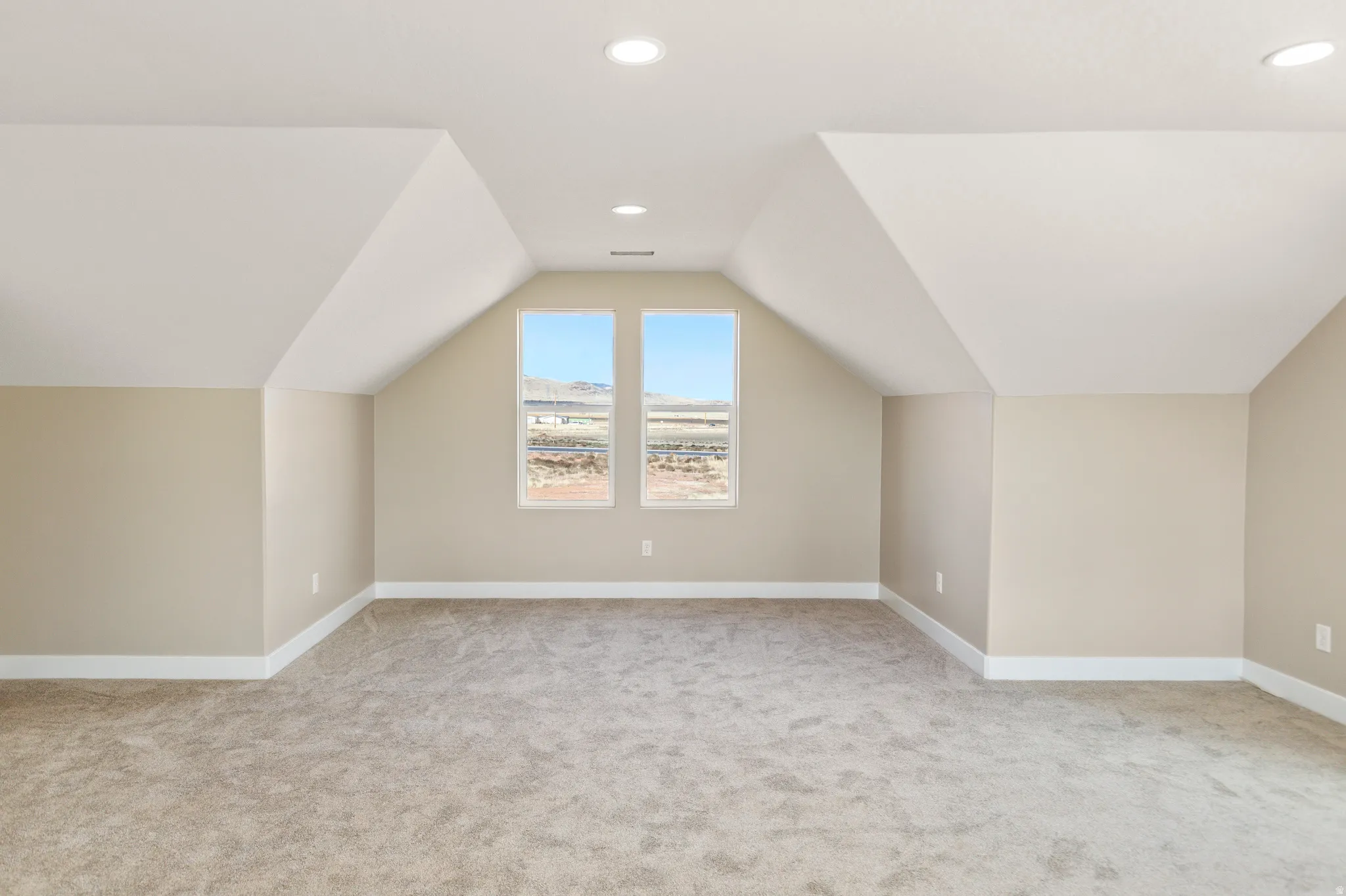 Additional living space featuring vaulted ceiling, light colored carpet, and recessed lighting