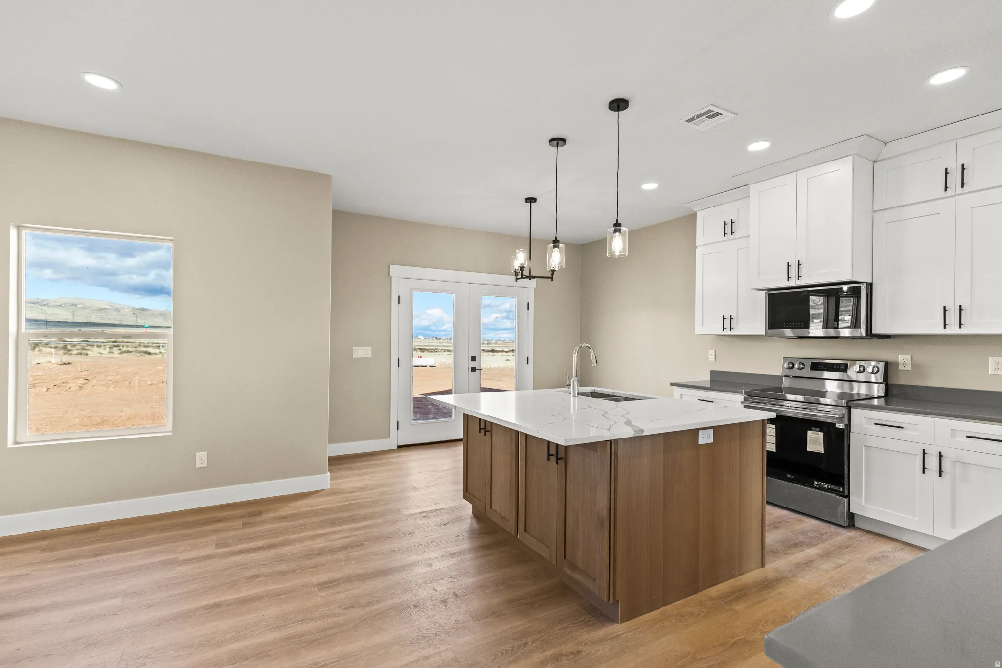 Kitchen with french doors, appliances with stainless steel finishes, recessed lighting, white cabinetry, and hanging light fixtures