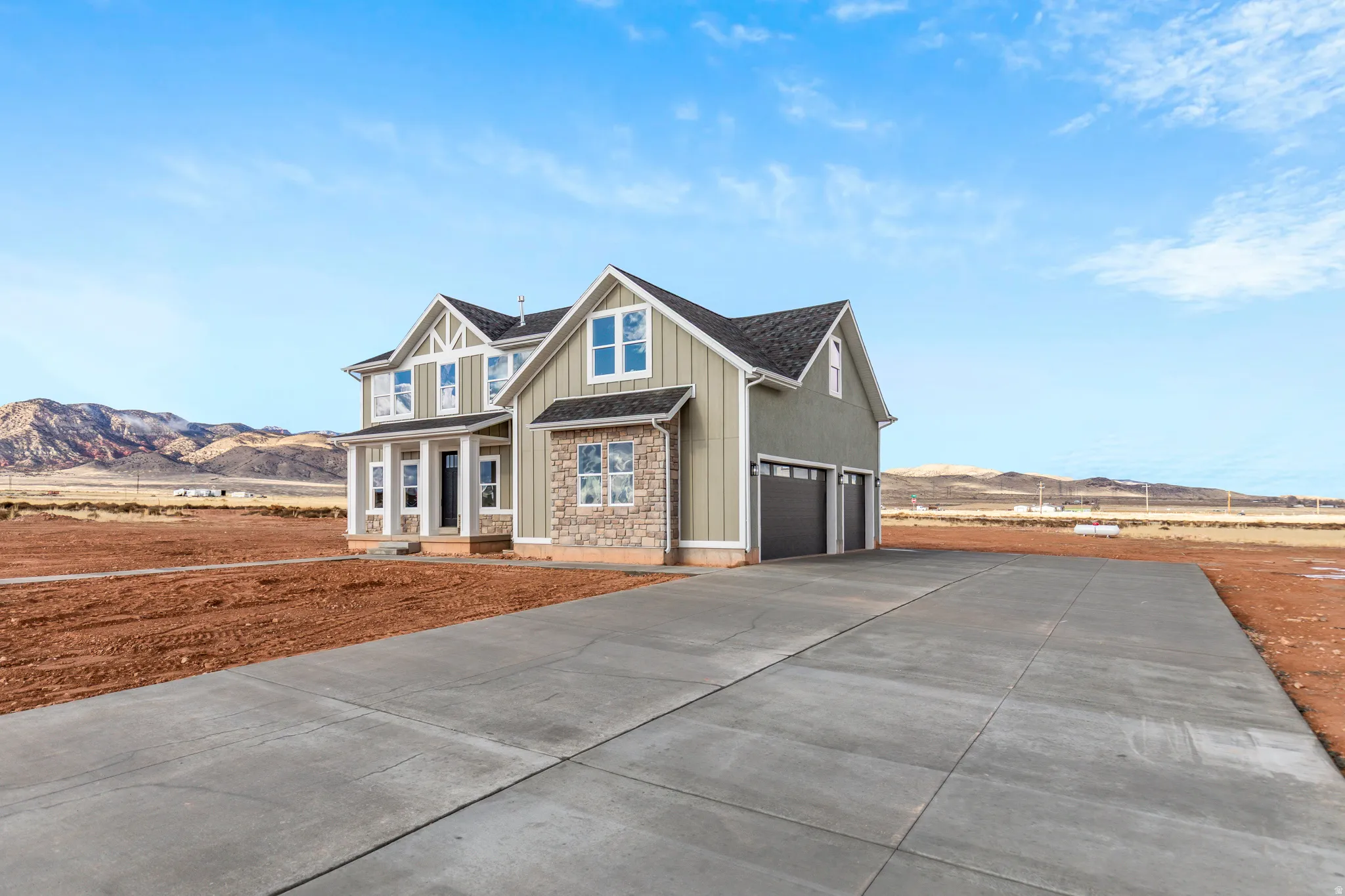 View of front facade featuring concrete driveway, a garage, a porch, board and batten siding, and a mountain view