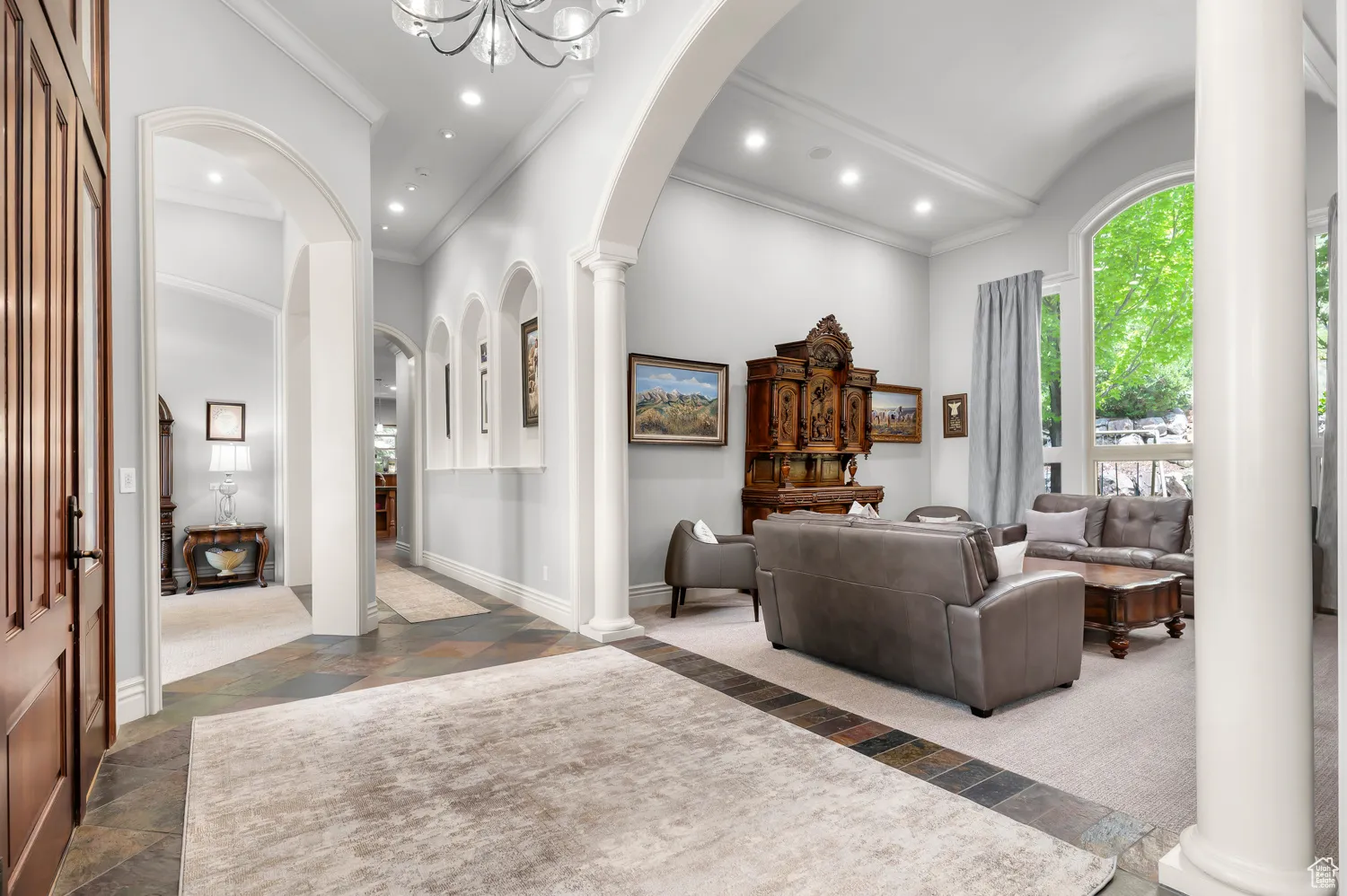Foyer entrance with stone tile flooring, ornamental molding, arched walkways, baseboards, and recessed lighting