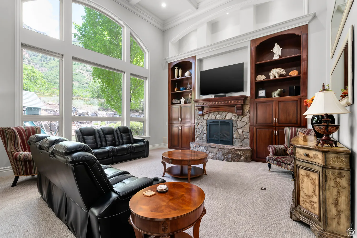 Carpeted living room with ornamental molding, a fireplace, a towering ceiling, beamed ceiling, and coffered ceiling