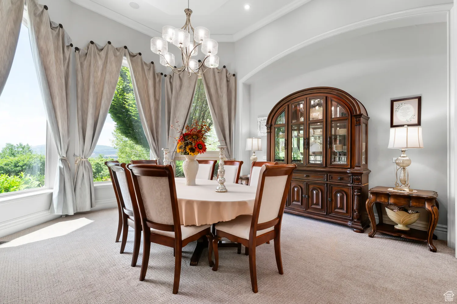 Dining area featuring light colored carpet, a chandelier, and crown molding