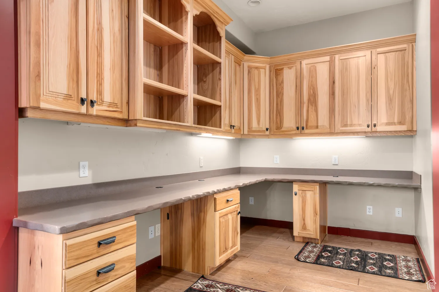 Unfurnished office featuring built in desk, light wood-style flooring, and baseboards