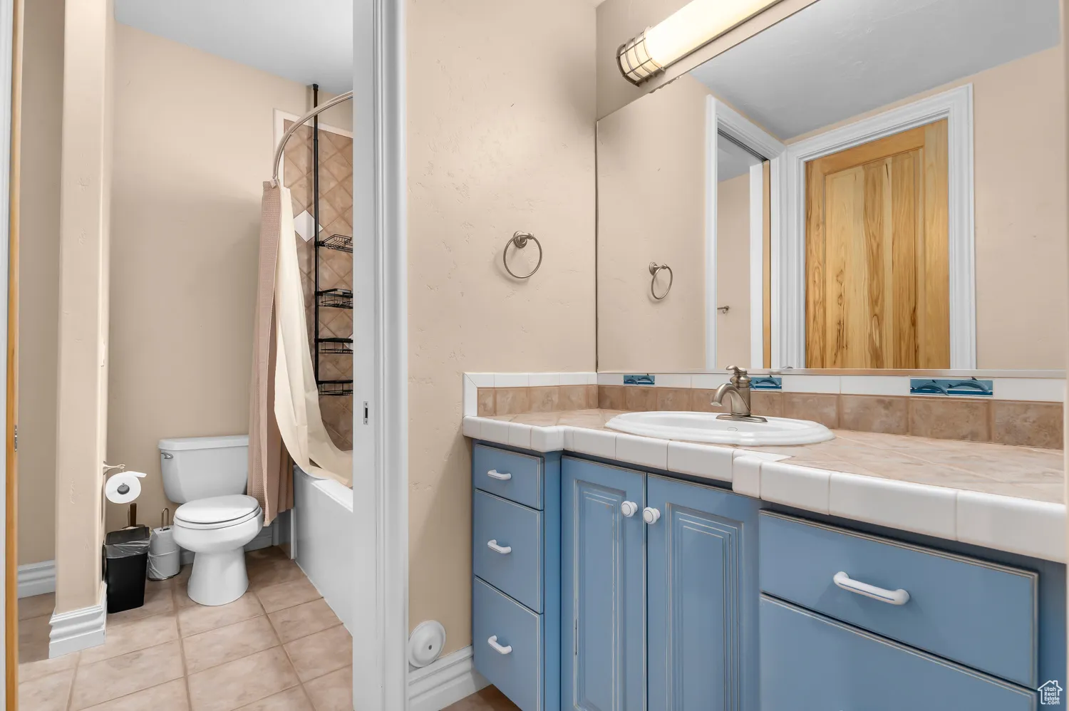 Bathroom featuring vanity, tile patterned flooring, shower / bath combination with curtain, and toilet