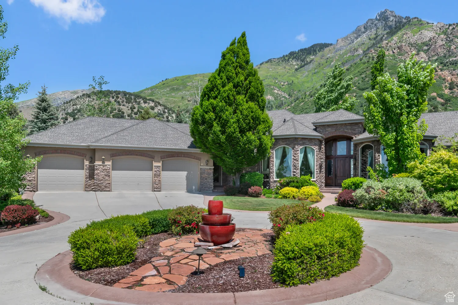 View of front facade featuring stone siding, a garage, a mountain view, and concrete driveway