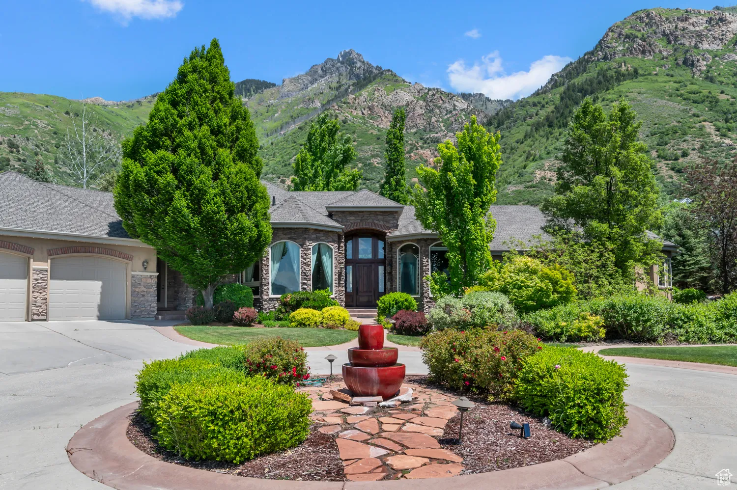 French country inspired facade with stone siding, a garage, a mountain view, and concrete driveway