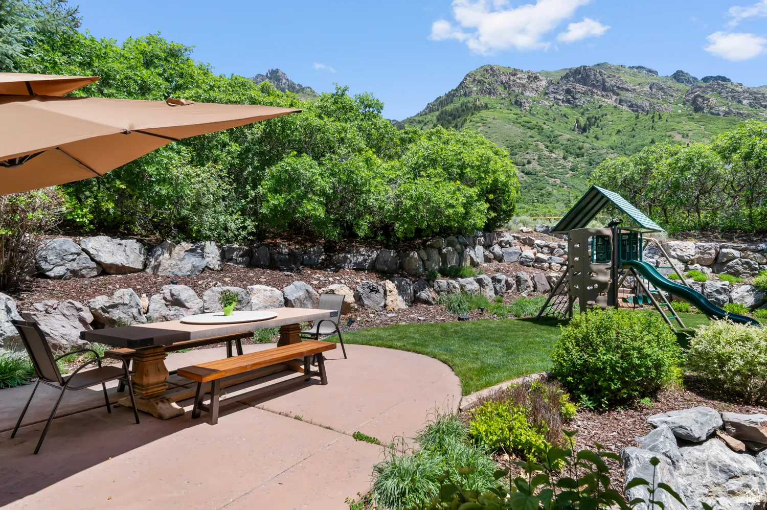 View of patio with outdoor dining area, a mountain view, and a playground