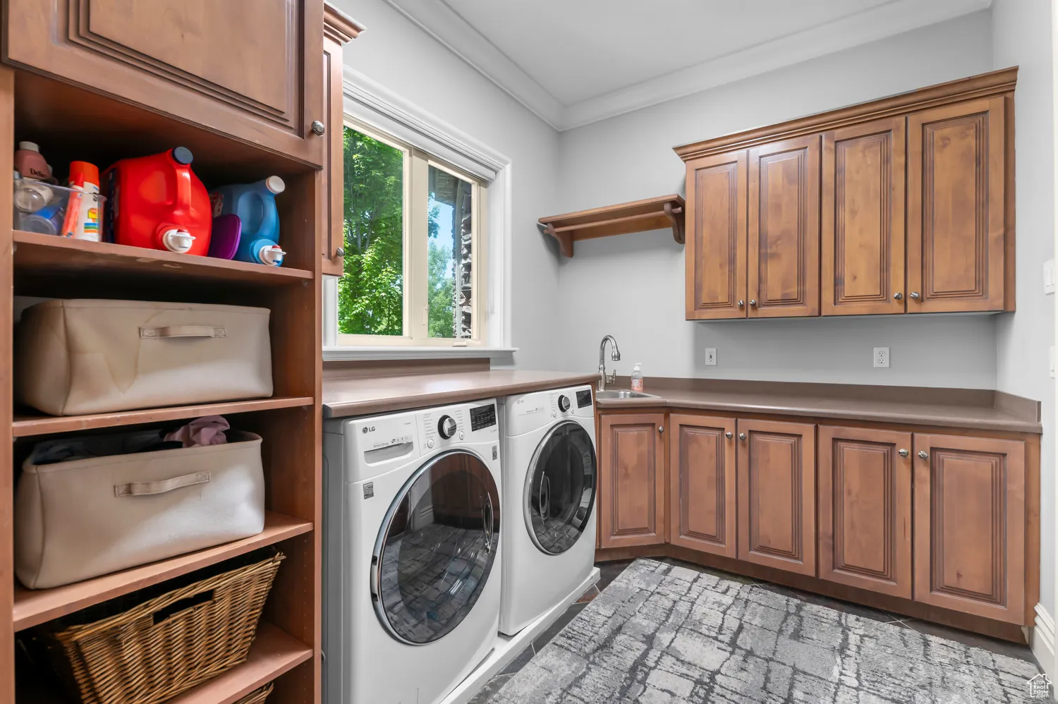 Washroom with washer and clothes dryer, crown molding, and cabinet space