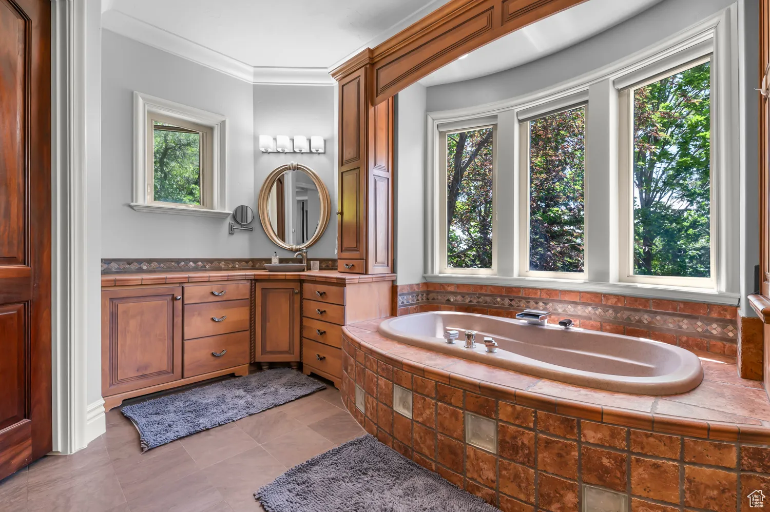 Full bath with plenty of natural light, vanity, a bath, and ornamental molding