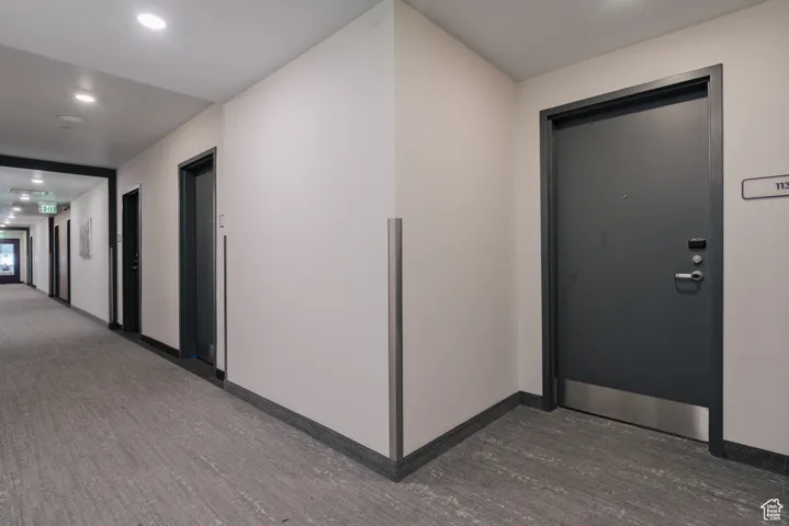 Corridor with dark wood-style flooring, baseboards, and recessed lighting
