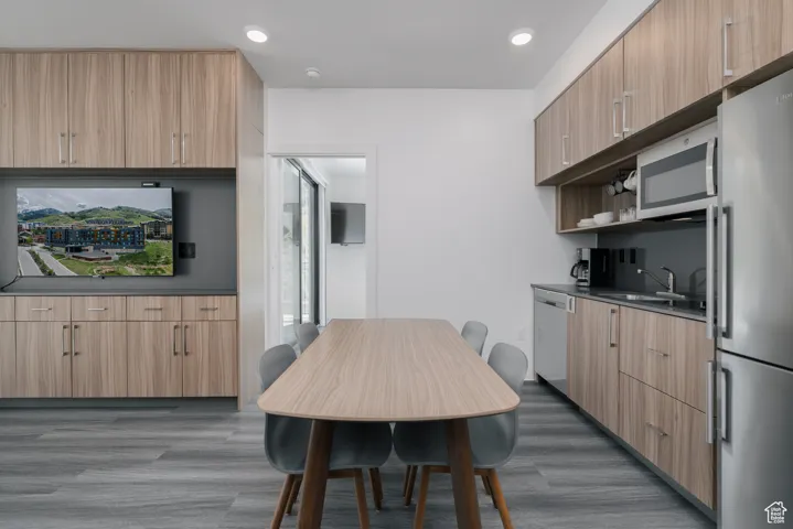 Kitchen featuring appliances with stainless steel finishes, a sink, dark wood-style floors, dark countertops, and light brown cabinets