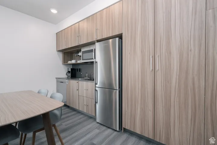 Kitchen featuring appliances with stainless steel finishes, wood finished floors, a sink, modern cabinets, and open shelves