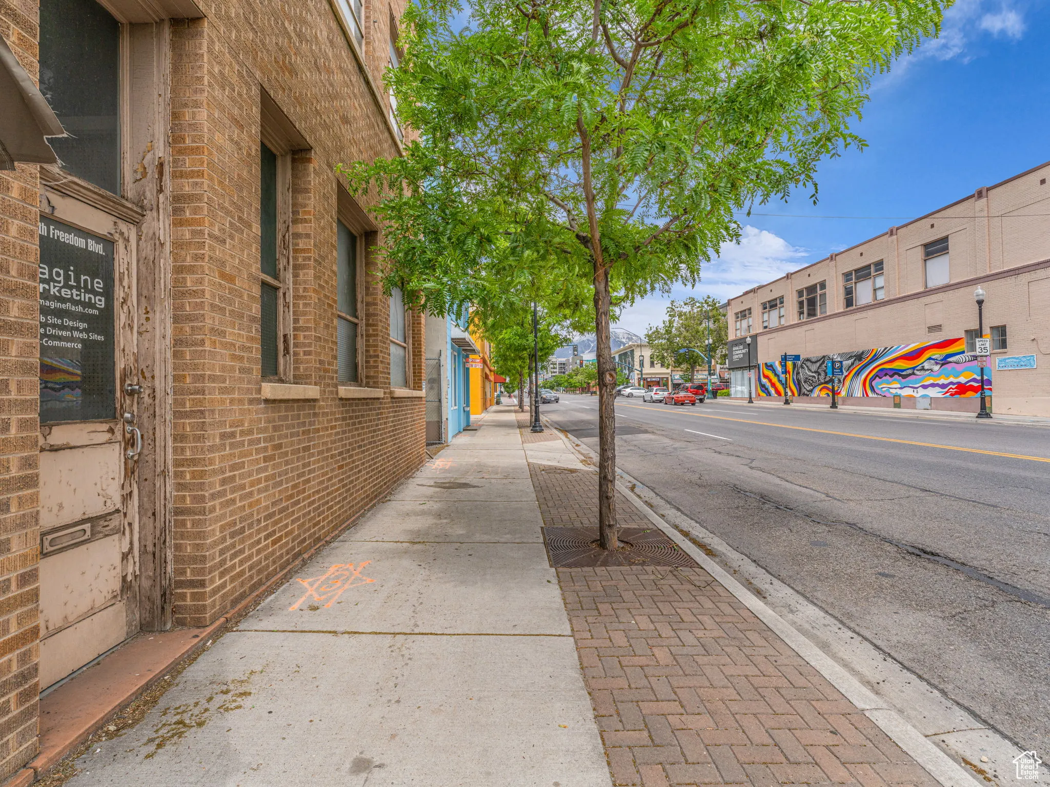 View of asphalt street with sidewalks, curbs, and street lights