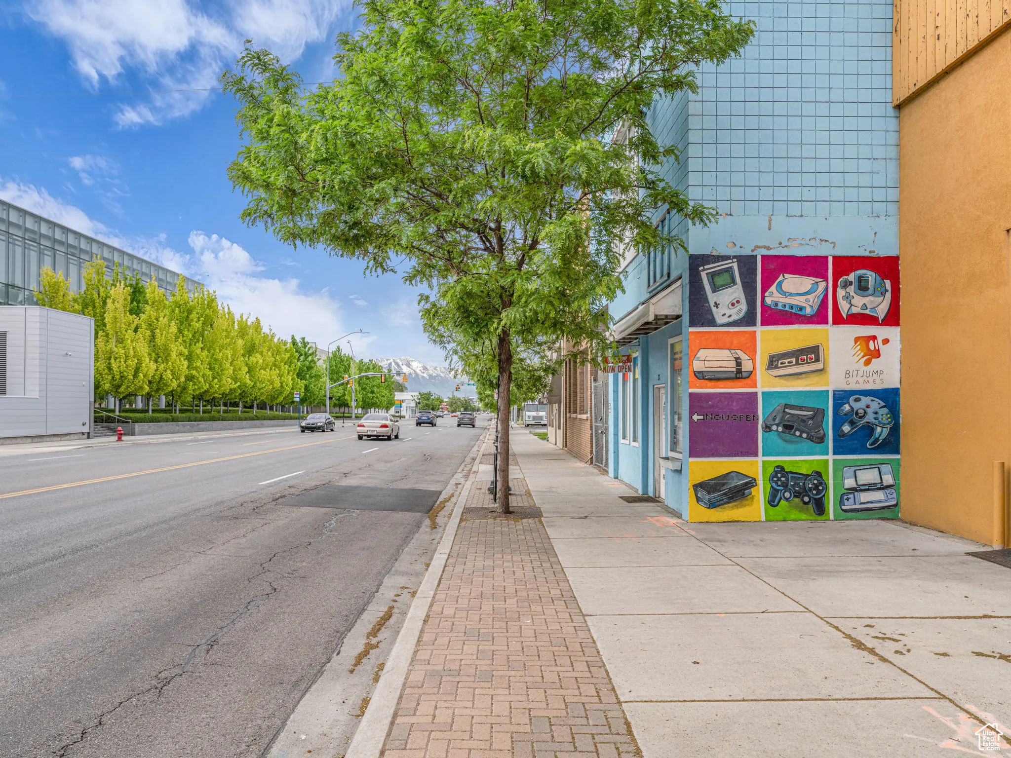 View of asphalt street featuring sidewalks, street lighting, and curbs