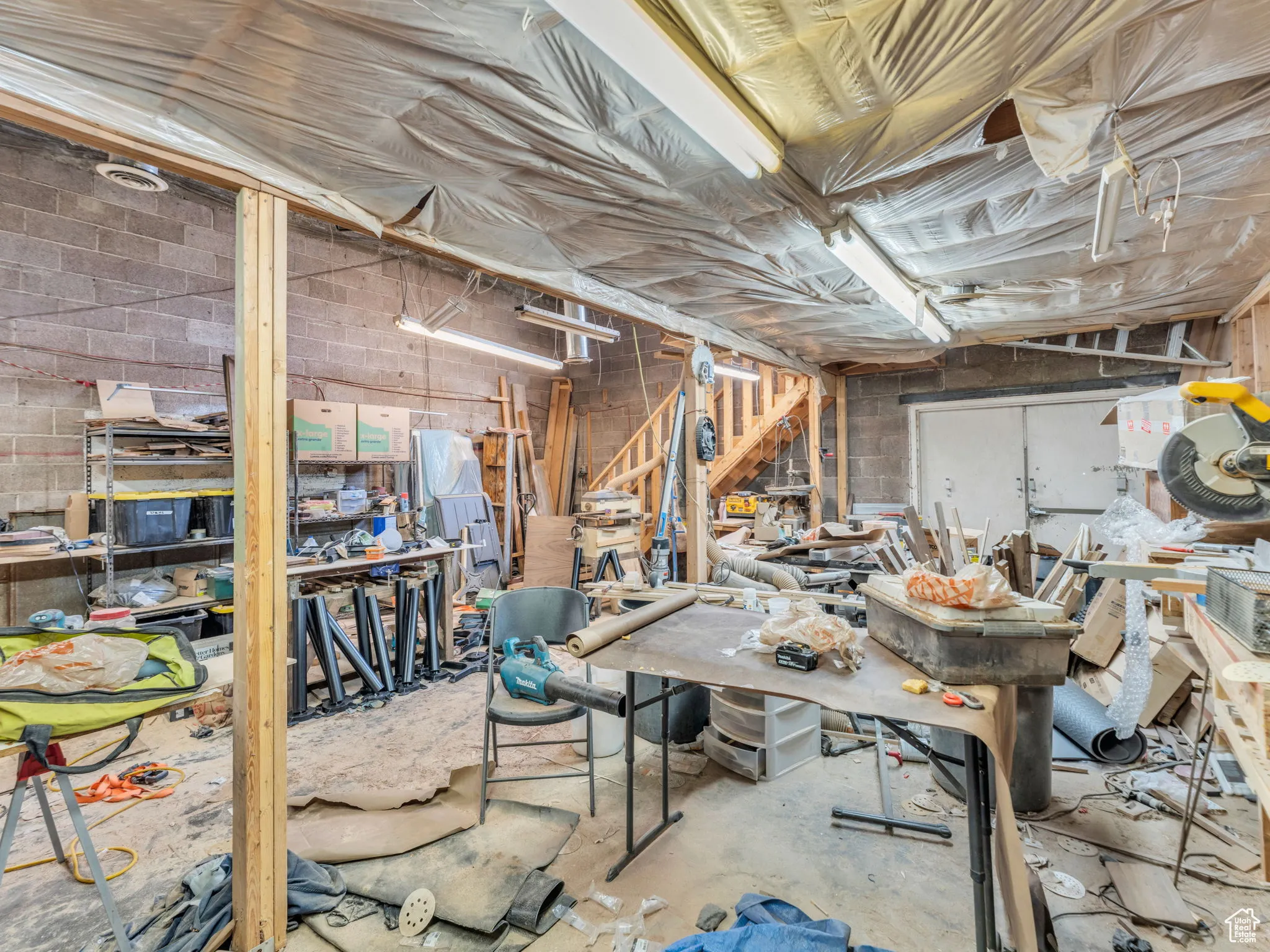 Unfinished basement featuring concrete block wall and a workshop area