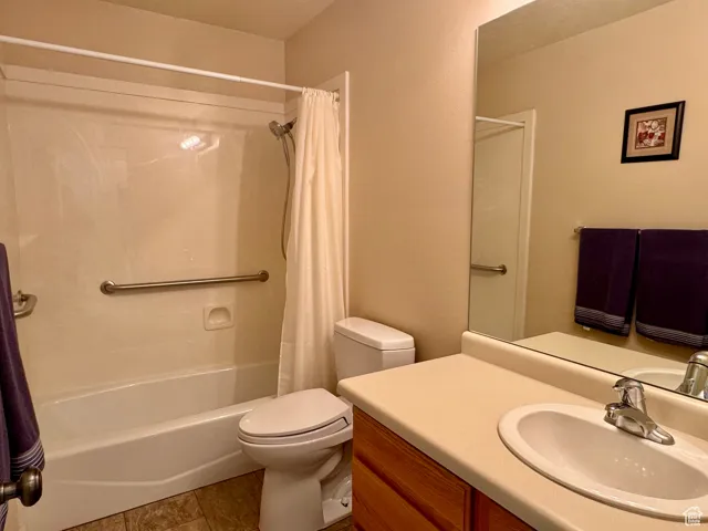 Full bathroom featuring shower / bathtub combination with curtain, vanity, toilet, and tile patterned floors