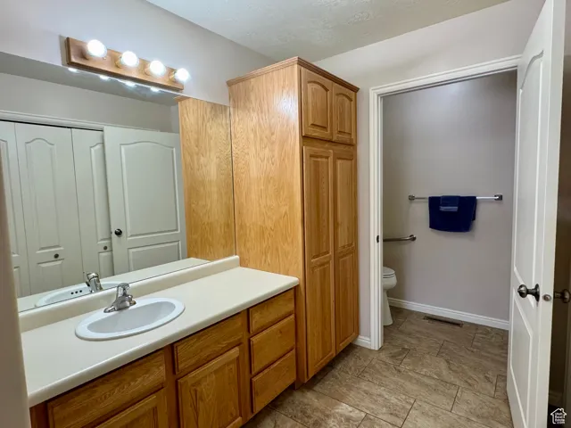 Bathroom with vanity, toilet, a closet, and baseboards